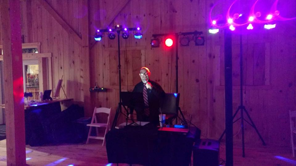 Professional DJ entertainment setup with speakers, lighting, and a lively reception atmosphere